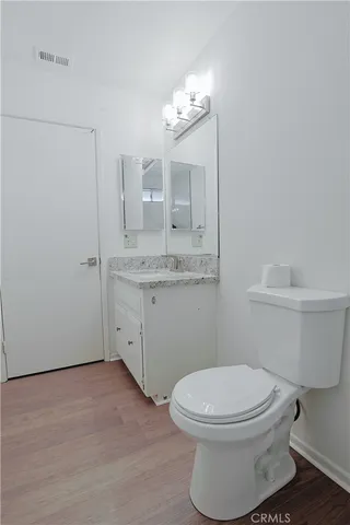 a bathroom with a granite countertop toilet a sink and a mirror
