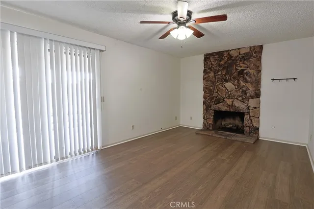 an empty room with windows a fireplace and wooden floor