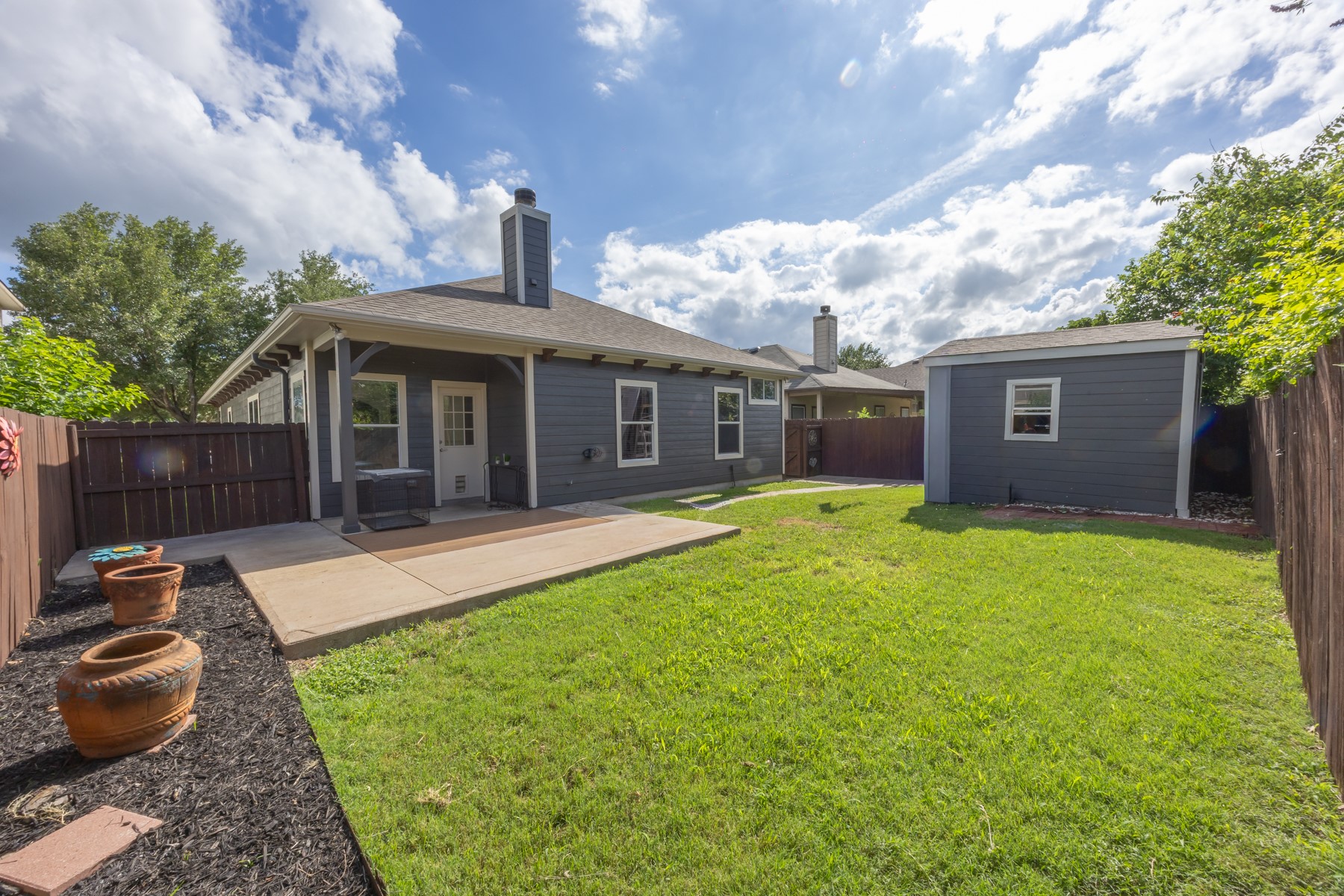 11500 Dimmit Street Manor, TX 78653 - Photo 14 of 14 Expansive backyard featuring a lush lawn, a concrete patio, and a detached shed