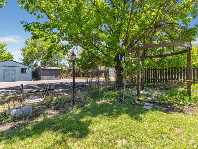 12825 South Fort Street Draper, UT 84020 - Photo 30 of 52 Expansive green lawn featuring a large mature tree, a decorative metal gazebo with a swing, and a black picket fence