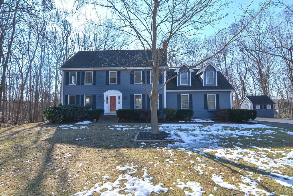 a front view of a house with yard and trees in the background