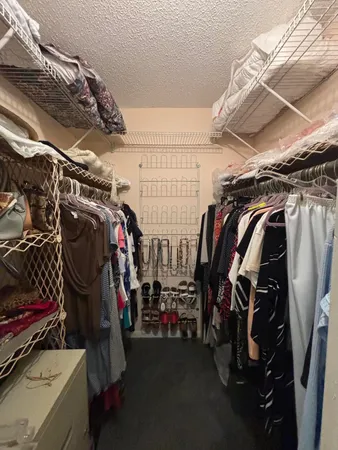 a view of walk in closet with clothes and shoes
