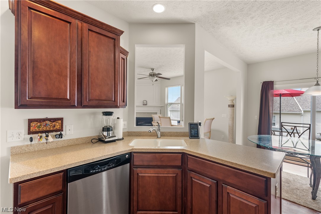 3967 Gardiner Run Akron, OH 44321 - Photo 12 of 35 Kitchen with stainless steel dishwasher, a textured ceiling, light countertops, dark brown cabinets, light hardwood floors, and ceiling fan