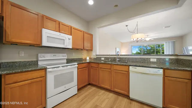 a kitchen with stainless steel appliances granite countertop wooden cabinets granite counter tops and a hard wood floors