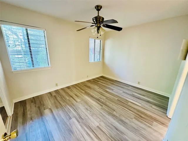 a view of empty room with wooden floor and fan