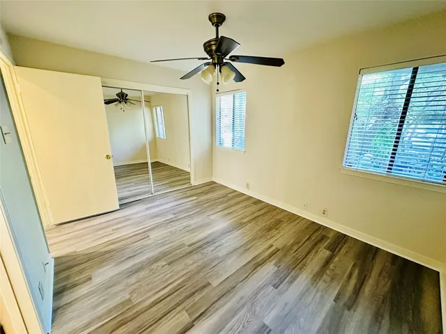 a view of empty room with wooden floor and fan
