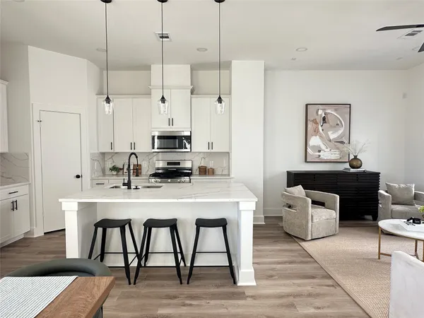 a kitchen with stainless steel appliances granite countertop a dining table chairs refrigerator and sink