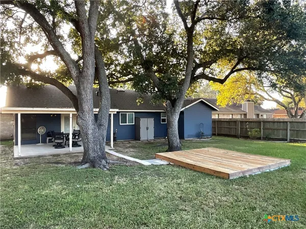 a view of a house with a yard and large tree