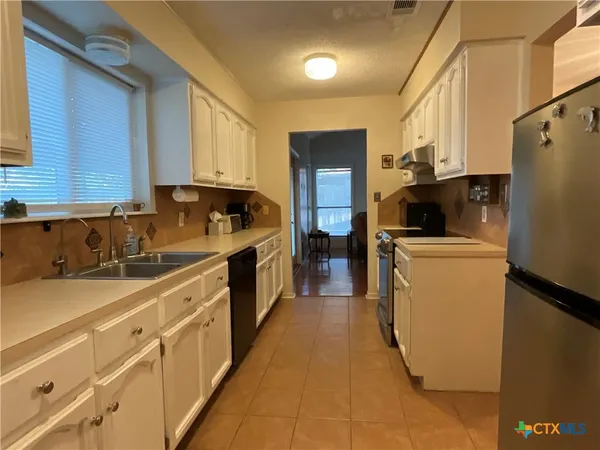 a kitchen with sink a refrigerator and cabinets