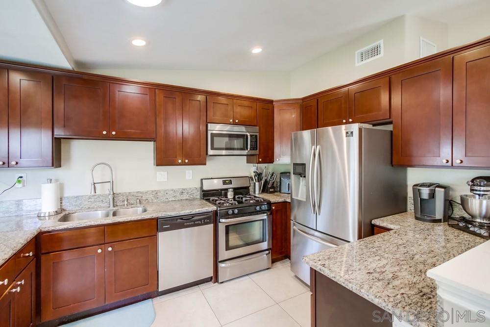 a kitchen with granite countertop stainless steel appliances cabinets a sink and a counter top space