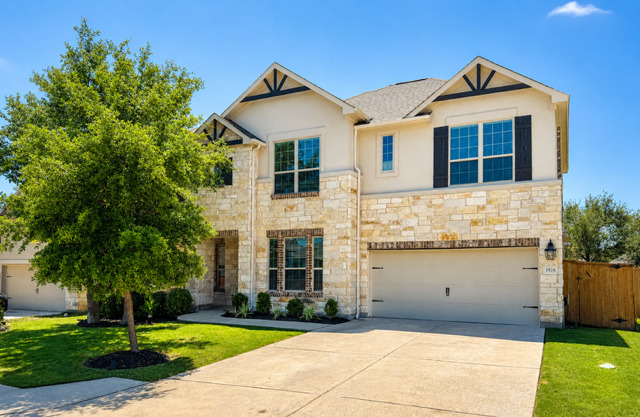 1928 Lakeside Ranch Road Georgetown, TX 78633 - Photo 2 of 37 A well-maintained two-story residence with a concrete driveway and lush green landscaping.
