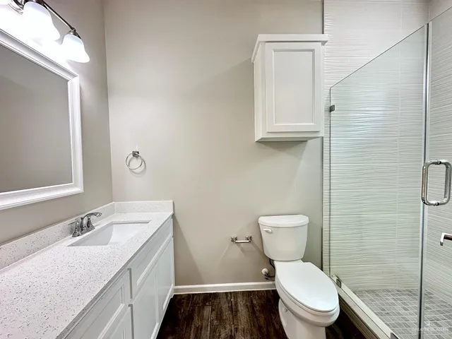a bathroom with a granite countertop toilet sink and mirror