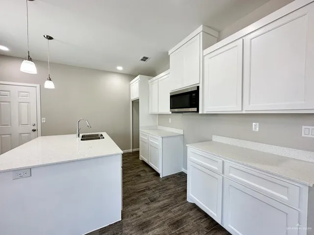 a kitchen with a sink a microwave and cabinets