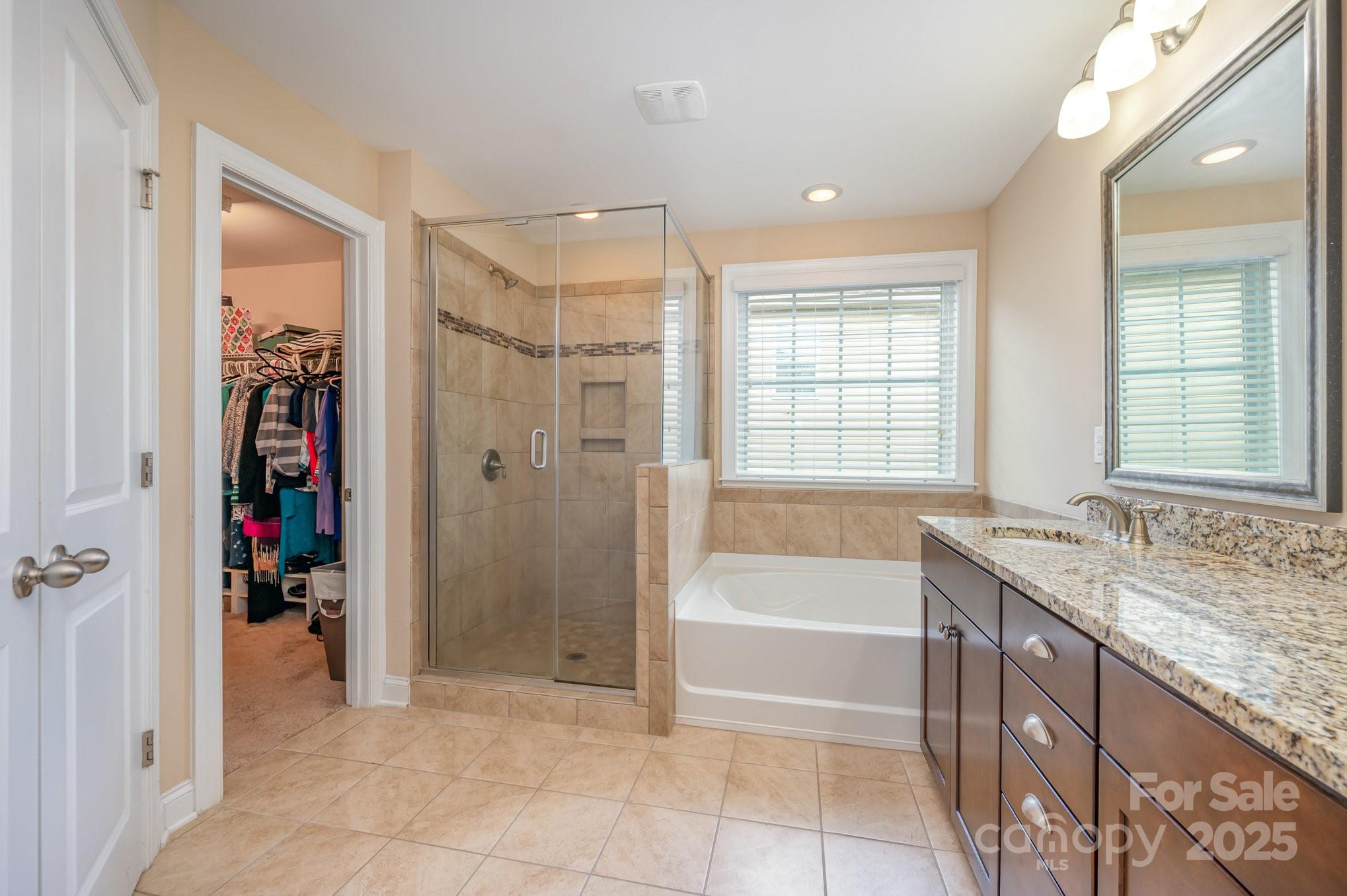 819 Coralbell Way Tega Cay, SC 29708 - Photo 17 of 33 a spacious bathroom with a granite countertop tub shower sink and mirror