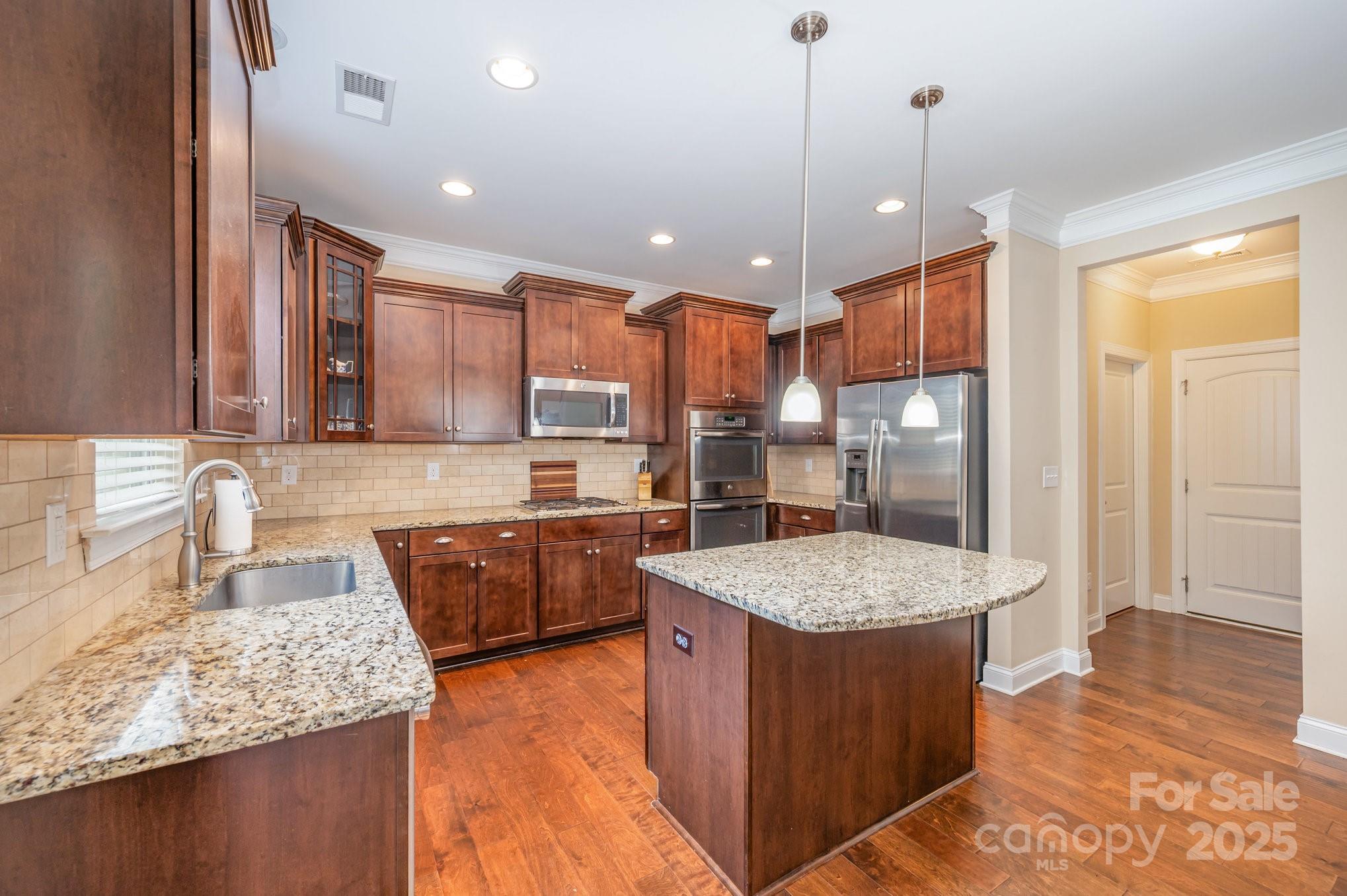 819 Coralbell Way Tega Cay, SC 29708 - Photo 10 of 33 a large kitchen with kitchen island granite countertop wooden cabinets a granite counter tops and a view of living room