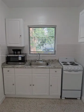 a kitchen with granite countertop white cabinets and a stove