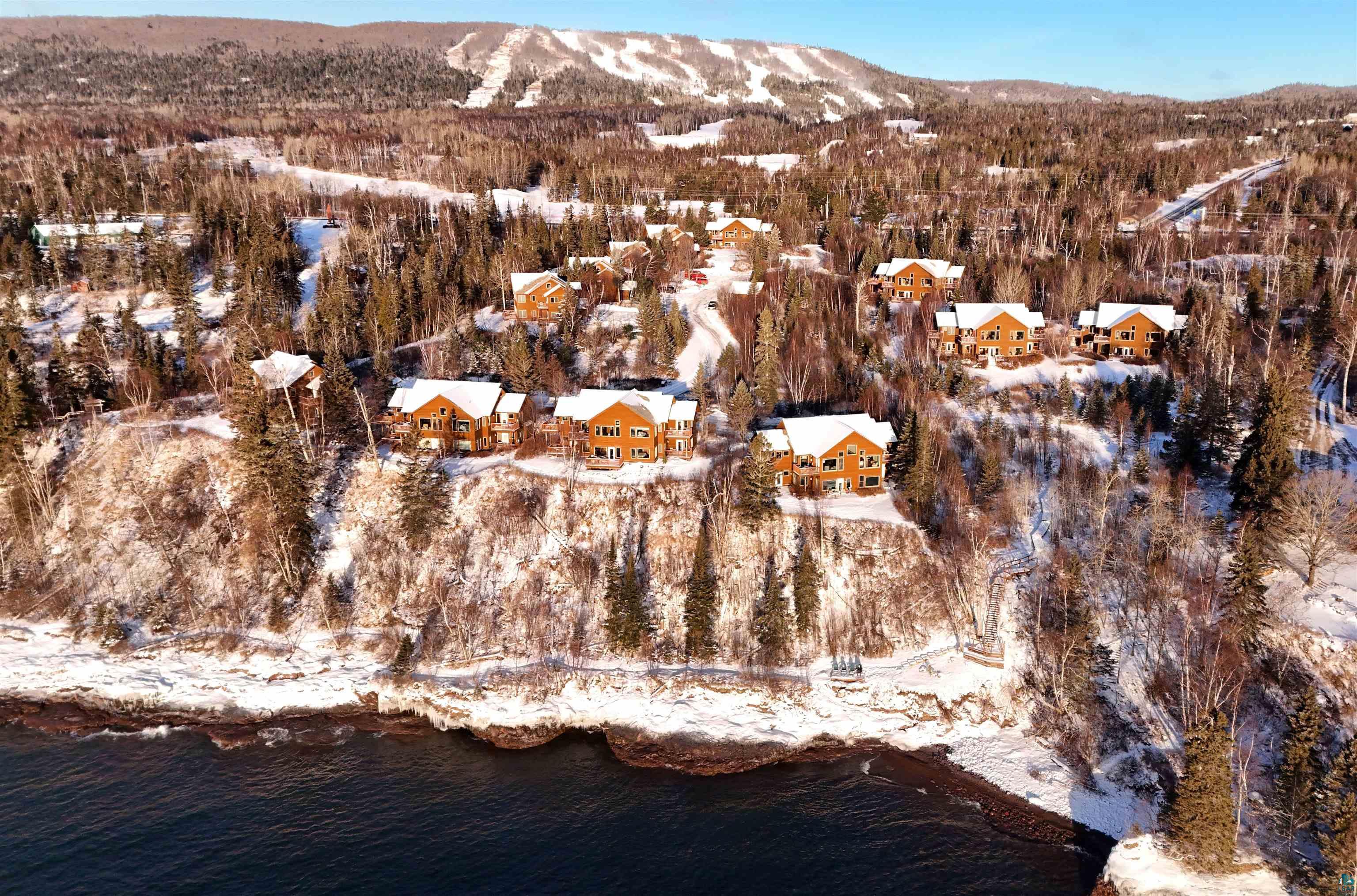 504-506 Poplar River Road, Unit 505 Lutsen, MN 55612 - Photo 2 of 39 Waterfront properties with rustic architecture, surrounded by evergreen forests, featuring a snow-covered landscape and distant mountain terrain
