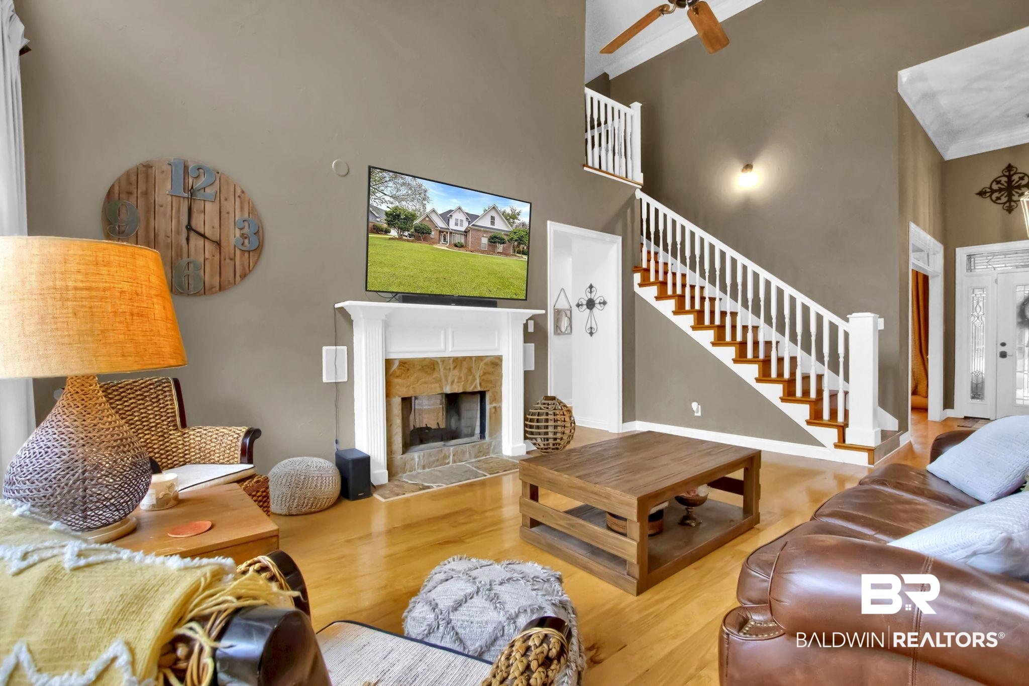 9002 Parliament Circle Daphne, AL 36526 - Photo 13 of 73 Living room with a high ceiling, ceiling fan, a double sided fireplace, and light hardwood floors, accent lighting.
