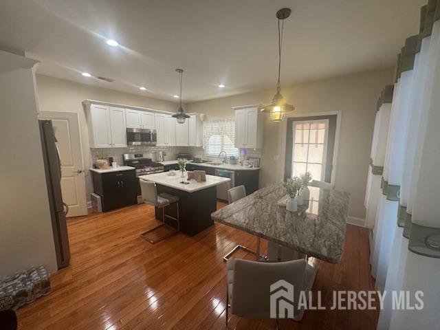 354 Cliff Road, Unit 2 Sewaren, NJ 07077 - Photo 4 of 11 a kitchen with kitchen island a stove a refrigerator a sink a dining table and chairs