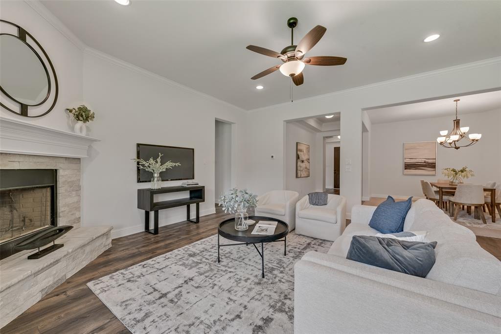 704 Toby Trail Mansfield, TX 76063 - Photo 16 of 40 Living area featuring crown molding, dark wood-style floors, a fireplace, ceiling fan, and a chandelier