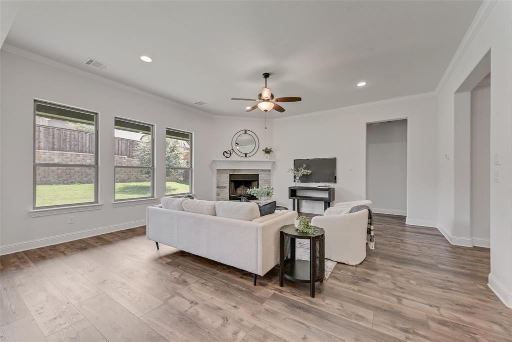 704 Toby Trail Mansfield, TX 76063 - Photo 17 of 40 Living area featuring a stone fireplace, ornamental molding, a ceiling fan, light wood-type flooring, and recessed lighting