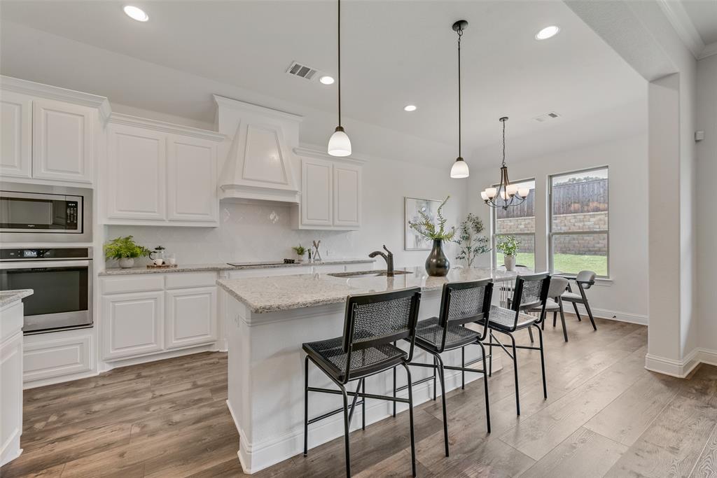 704 Toby Trail Mansfield, TX 76063 - Photo 21 of 40 Kitchen with light stone counters, appliances with stainless steel finishes, light wood-type flooring, decorative light fixtures, and recessed lighting