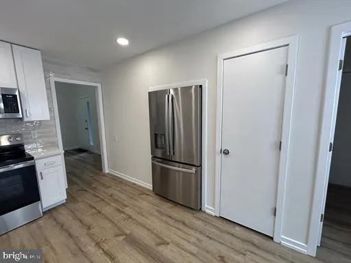 a kitchen with a refrigerator stove and wooden floor