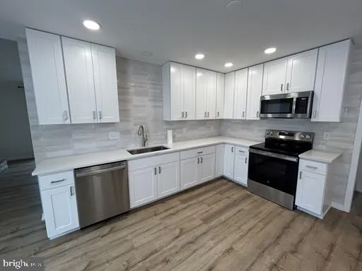 a kitchen with granite countertop a sink cabinets and stainless steel appliances