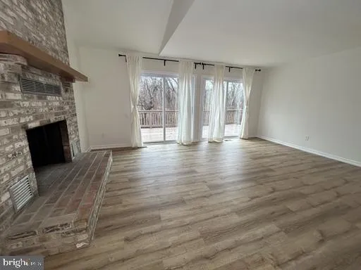 a view of empty room with wooden floor and fireplace