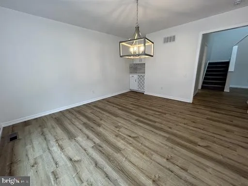a view of empty room with wooden floor and chandelier