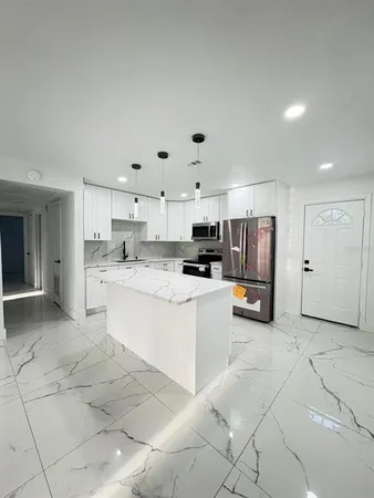 a large white kitchen with stainless steel appliances granite countertop a sink and cabinets
