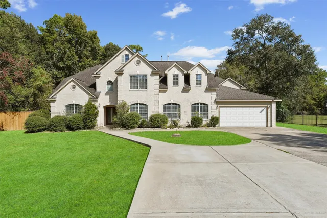 a view of a white house with a yard and large trees