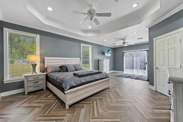a spacious bedroom with a large bed a chandelier and windows