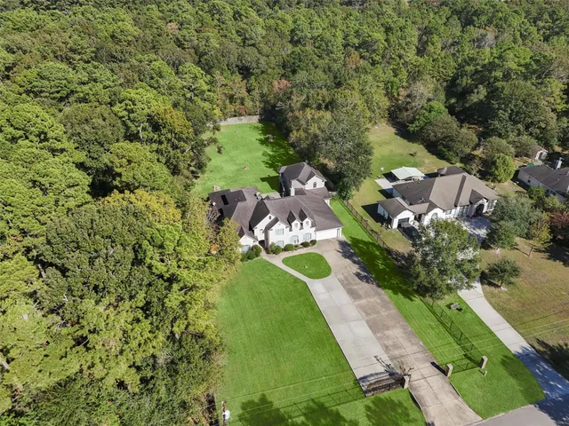 an aerial view of residential house with outdoor space and trees all around