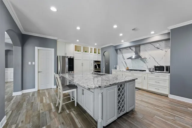 a kitchen with stainless steel appliances double vanity sink and wooden floor