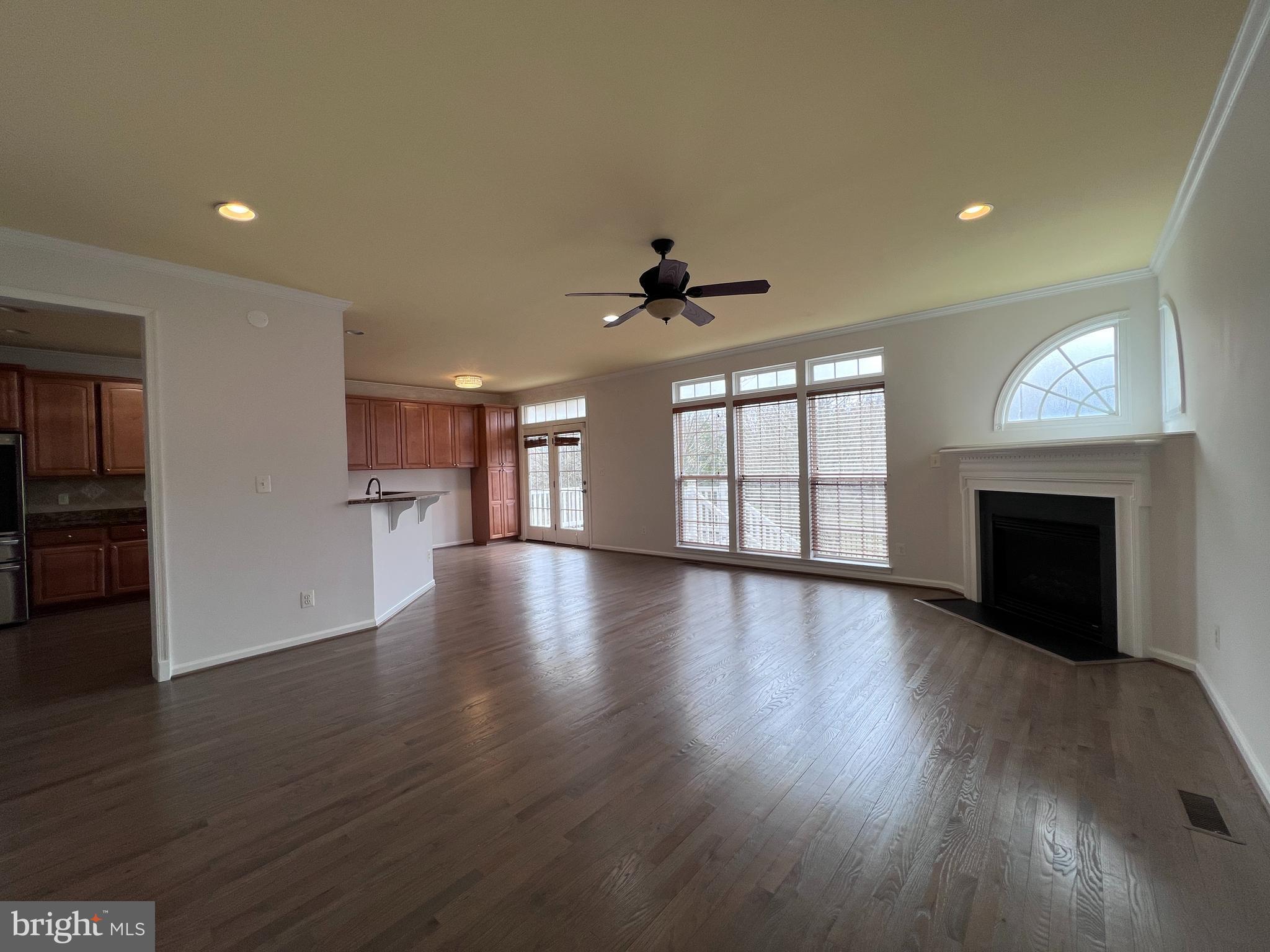 3925 Beeker Mill Place Chantilly, VA 20151 - Photo 4 of 40 an empty room with wooden floor fireplace and windows