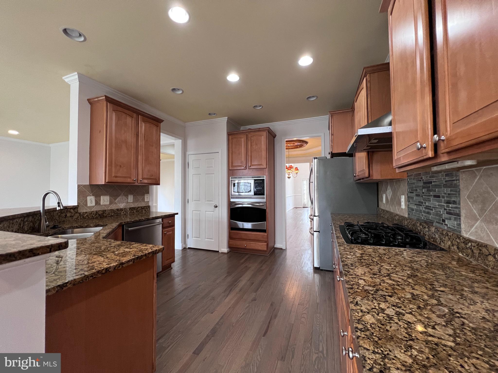3925 Beeker Mill Place Chantilly, VA 20151 - Photo 8 of 40 a kitchen with granite countertop a refrigerator and a stove top oven