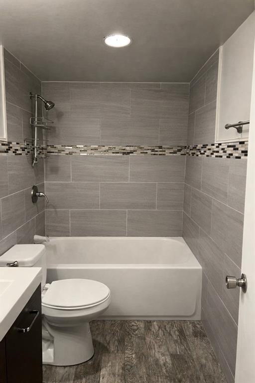 3121 Rosedale Avenue University Park, TX 75205 - Photo 10 of 16 Planned Full bathroom featuring a white tub, shower with gray tile surround and mosaic accent, white toilet, and wood-finish flooring