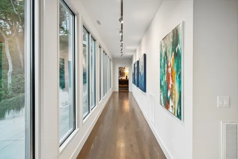 a view of a hallway with wooden floor and a bathroom