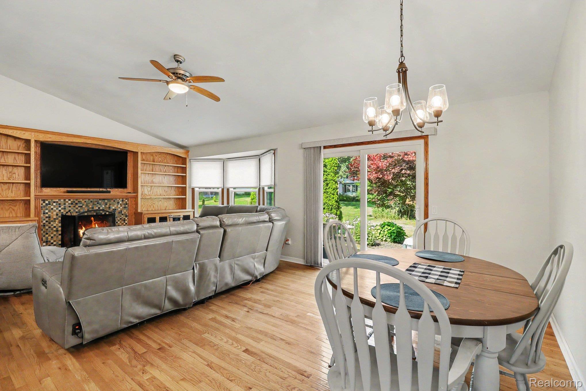 24404 Jamestowne Road Novi, MI 48375 - Photo 6 of 26 Wood-finish flooring throughout, vaulted ceiling, built-in shelving, fireplace with tile surround, and bay windows