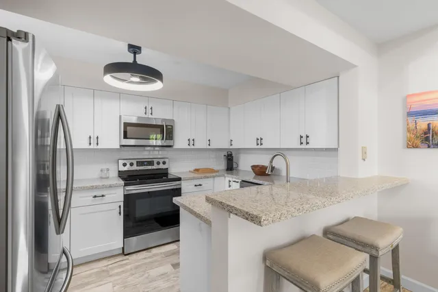 a kitchen with stainless steel appliances granite countertop a stove refrigerator sink and microwave