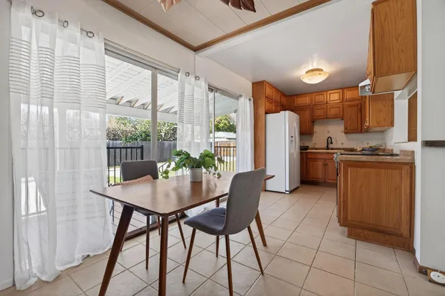 a kitchen with stainless steel appliances granite countertop a stove a refrigerator a dining table and chairs with wooden floor