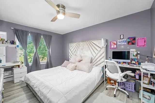 a bedroom with a bed a desk and chair with a window