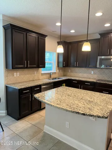 a kitchen with kitchen island a counter space a sink appliances and cabinets