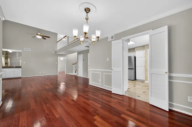 a view of a hallway with wooden floor and chandelier