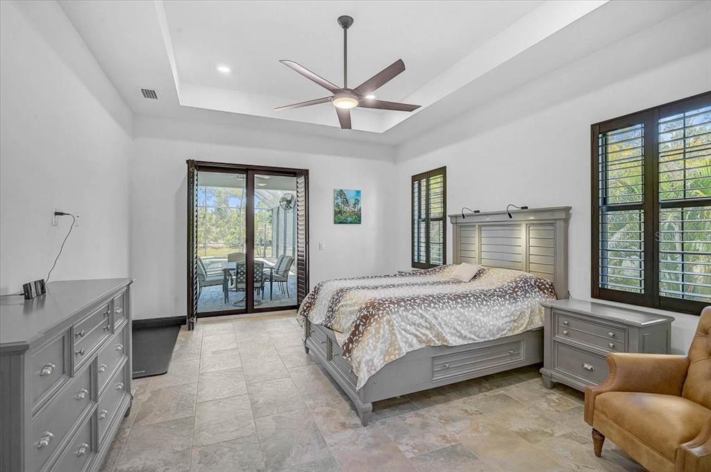 113 Burney Road Osprey, FL 34229 - Photo 19 of 42 a spacious bedroom with a large bed and a chandelier