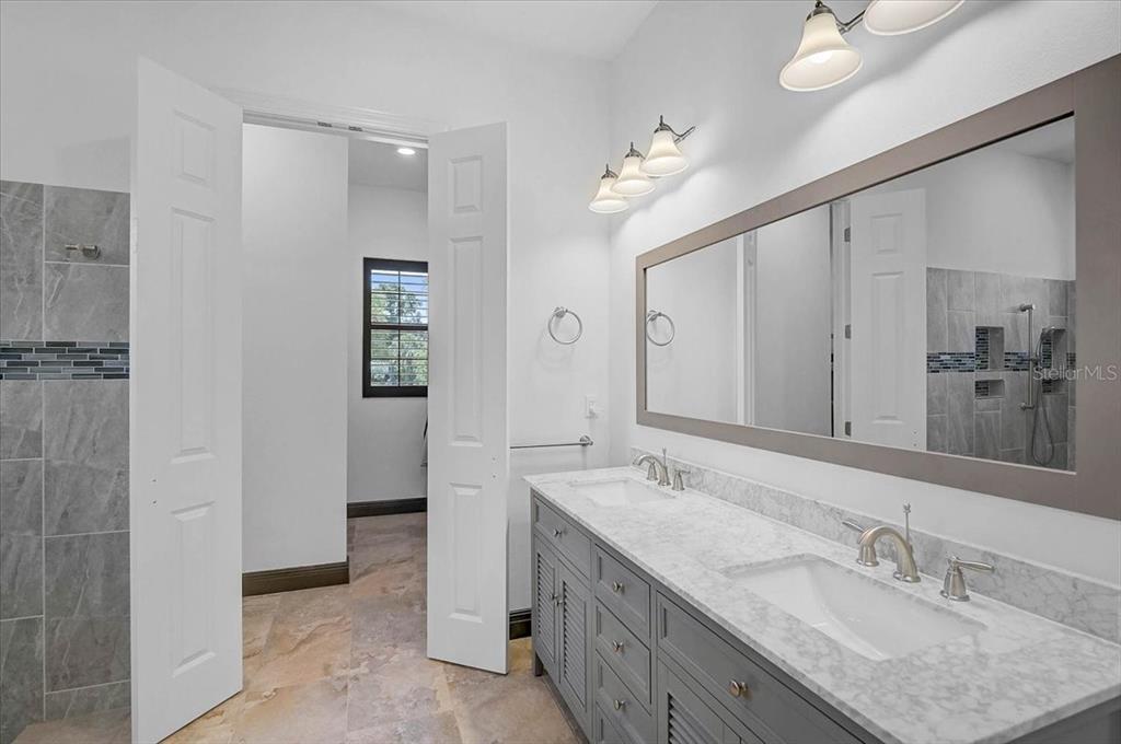 113 Burney Road Osprey, FL 34229 - Photo 21 of 42 a bathroom with a granite countertop double vanity sink a mirror and shower