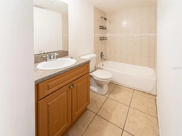 a bathroom with a granite countertop sink a toilet mirror and bathtub