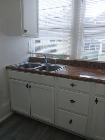 a kitchen with granite countertop white cabinets and a sink