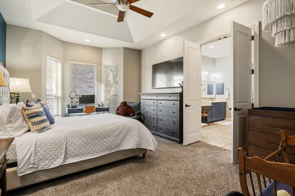 a bedroom with a bed a chandelier and flat screen tv